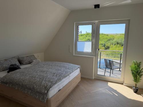 a bedroom with a bed and a large window at BeachHus 35, Whg 4 in Sankt Peter-Ording