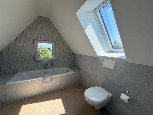 a bathroom with a toilet and a bath tub at BeachHus 35, Whg 4 in Sankt Peter-Ording
