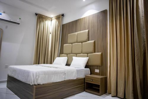 a bedroom with a bed with a large headboard at BBB Luxury Apartment in Amuwo