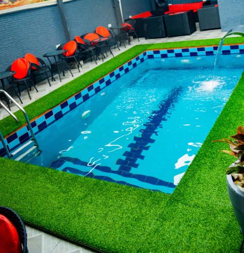 a swimming pool with green grass and red chairs at BBB Luxury Apartment in Amuwo