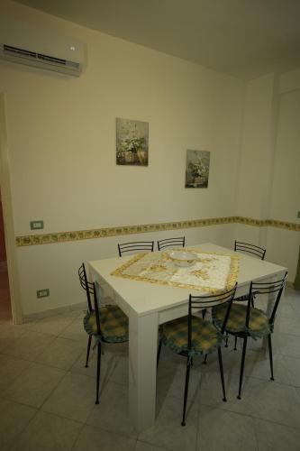a white table and chairs with a table and some paintings at Casa Dolce Armonia in Augusta