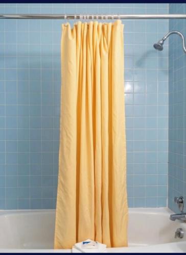 a bathroom with a yellow shower curtain next to a tub at EXECUTIVE INN & SUITES HIGHWAy US 59 in Lufkin