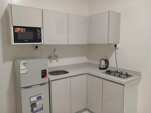 a small kitchen with white cabinets and a refrigerator at فيو بارك للاجنحة الفندقية in Al Kharj