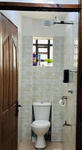 a bathroom with a white toilet in a room at Stylish Ngong Retreat with Balcony & Rooftop Lounge The Moon Stays in Ngong