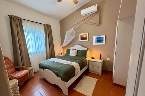 a bedroom with a bed and a chair and a window at Casa M&B in Las Galeras