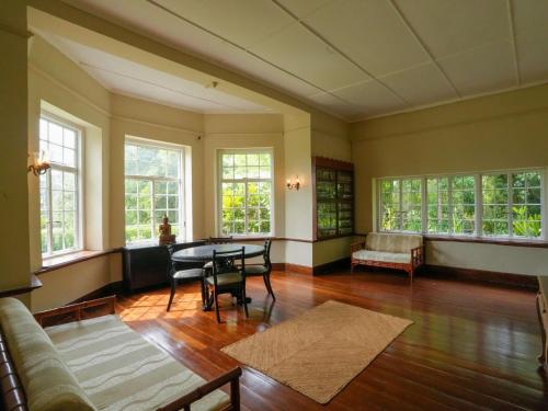 a living room with a table and chairs and windows at Graystone Bungalow by Seven Angels in Haputale