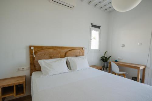 a bedroom with a white bed with a wooden headboard at Gazia Sea View House - Mykonos Town in Mikonos