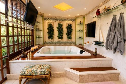 a large bathroom with a tub and a tv at Chalé Guararema in Petrópolis