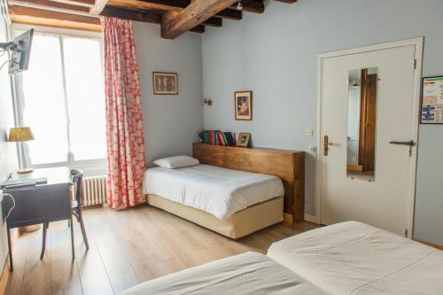 a bedroom with two beds and a desk and a window at Le Relais Des Templiers in Beaugency
