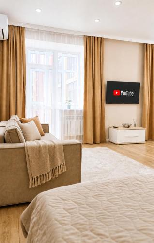 a bedroom with a bed and a tv on the wall at Студия ЖК "Кенесары" in Kokshetau