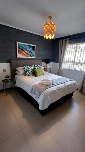 a bedroom with a large bed and a chandelier at Sea Spray Table View Beachfront Bliss in Cape Town