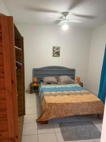 a bedroom with a bed and a ceiling fan at Villa Boat red in Quartier Morne Acajou