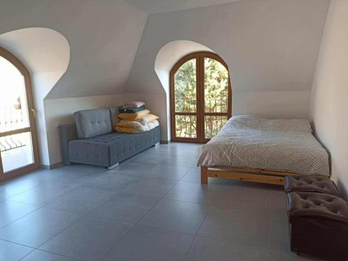 a bedroom with a bed and a couch and windows at Guest house in Wojtkowa