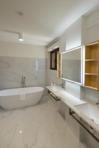 a white bathroom with a tub and a sink at KV Residences 