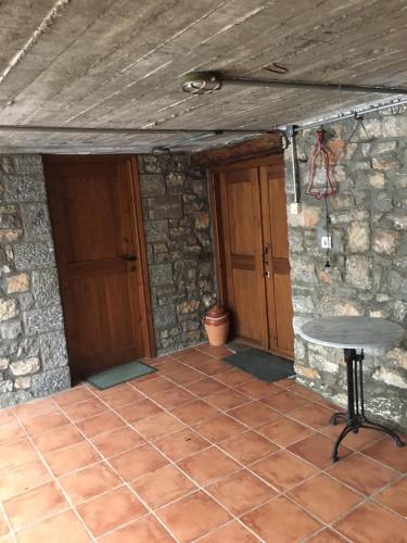 a patio with a table and a stone wall at Ξενώνας Το Πάλαι Ποτέ in Polydrossos