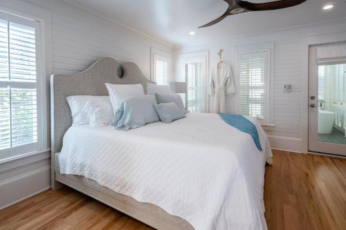a white bedroom with a large white bed with white pillows at Magnolia Honeymoon Cottage in Santa Rosa Beach