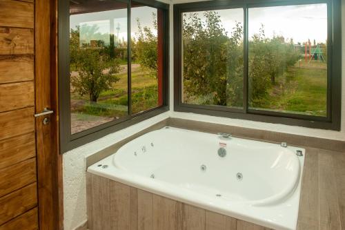 a bath tub in a bathroom with two windows at Cabañas Morita Mia in San Rafael