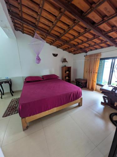 a bedroom with a bed with a purple bedspread at ponta gato residence in Tarrafal