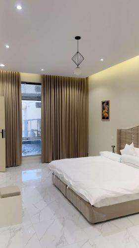 a large bedroom with a large bed and a large window at شاليهات الورد الفندقية in Ash Shuqayq