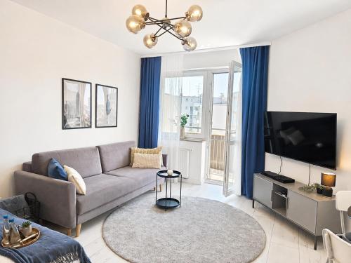 a living room with a couch and a tv at Kairos Apartments - Lothus - darmowy garaż podziemny, ścisłe centrum in Gliwice