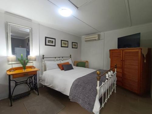 a bedroom with a bed and a table and a television at ROCKABILLY RANCH Self-Catering Guest Units in Pietermaritzburg
