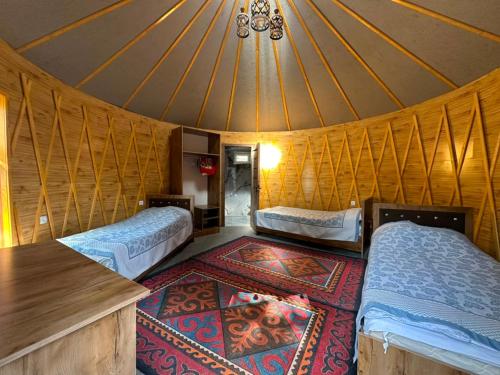 a room with two beds and a rug in a yurt at Датка in Arslanbob