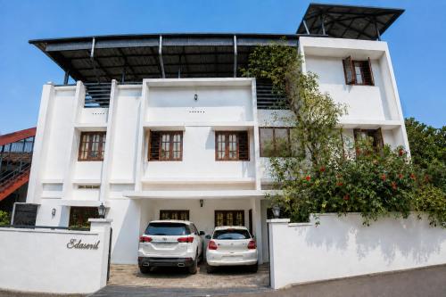 two cars parked in front of a white building at Hridyas in Ernakulam