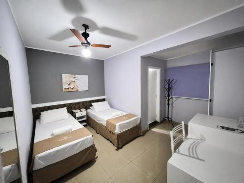a bedroom with two beds and a ceiling fan at Hotel Colonial in Pôrto Ferreira
