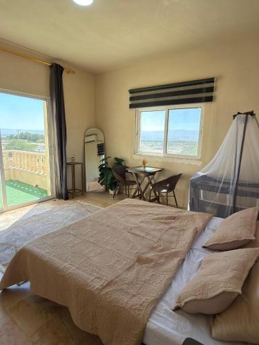 a bedroom with a large bed and a table at Entire Home Near Deadsea & Baptism Site Pool, Garden, BBQ, Great Price in Shūnat Nimrīn