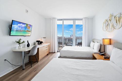 a hotel room with two beds and a desk and a window at Upper Studio Stunning Intracoastal Views in Hallandale Beach
