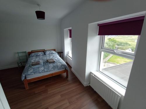 a small bedroom with a bed and a window at Mutton House in Milltown Malbay