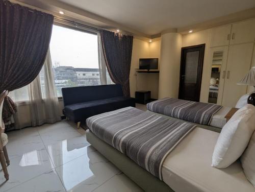 a hotel room with two beds and a couch at New Panoramic Hotel in Lahore