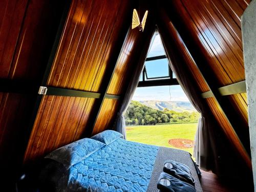 a bedroom with a bed in a room with a window at Refugio Pertinho do Céu in São Pedro