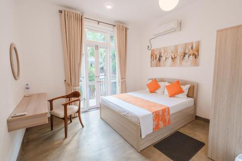 a bedroom with a bed and a desk and a window at Glowing Crescent Holiday Apartments in Rajagiriya