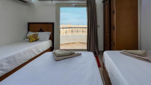 two beds in a room with a window at Atlantis Pyramids Inn in Giza