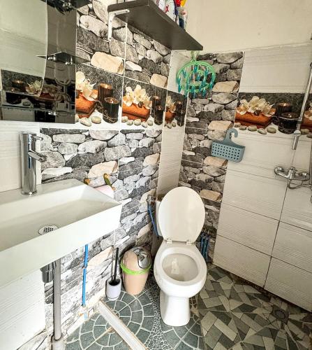 a bathroom with a toilet and a stone wall at L'échappée verte in Chirongui