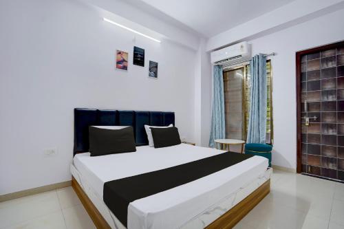 a bedroom with a white and black bed and a window at Hotel O City Star in Rewa