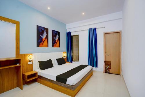 a bedroom with a large bed with blue curtains at Hotel O City Star in Rewa