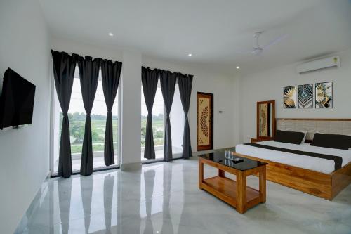 a bedroom with a bed and large windows at SPOT ON Golden Eagle Residency in Barpeta