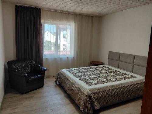 a bedroom with a bed and a chair and a window at Уютная Дача in Zatoka