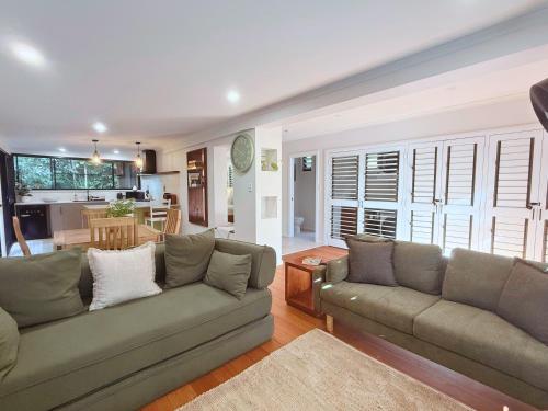 a living room with a couch and a kitchen at Private Rainforest Cottage - Bingil Bay in Mission Beach