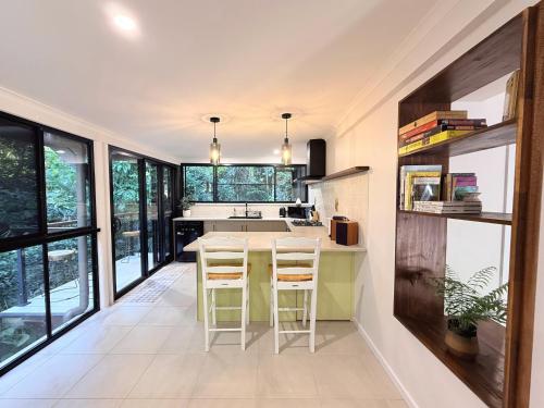 a kitchen with a table and chairs and windows at Private Rainforest Cottage - Bingil Bay in Mission Beach
