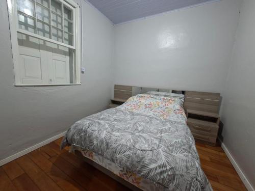 a small bedroom with a bed and a window at Casa Finger próx do Centro e do Núcleo de Casas Enxaimel ambiente familiar in Ivoti