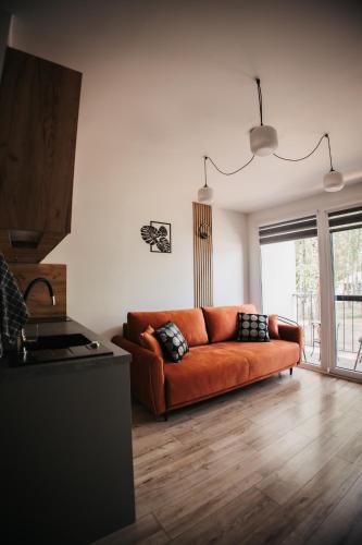 a living room with an orange couch in a room at Apart & Plus 1 in Okuninka