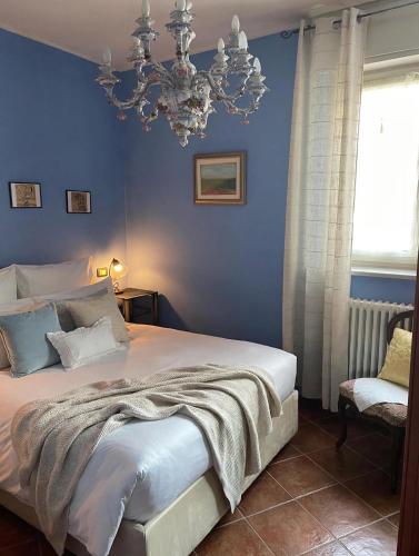 a blue bedroom with a bed and a chandelier at B&B Villa Giardini Susanna in Veruno