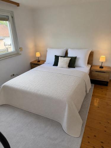 a bedroom with a large white bed with two lamps at Danube Lodge in Hüfingen