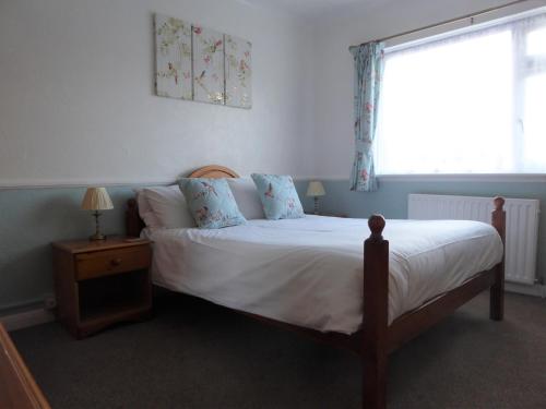 a bedroom with a bed with white sheets and a window at The Denewood in Sandown