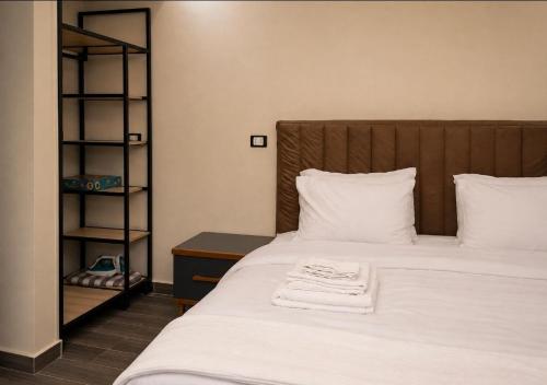 a bed with white sheets and a wooden head board at Pyramids Gardens 2bedroom apartment in ‘Ezbet `Abd el-Ḥamîd