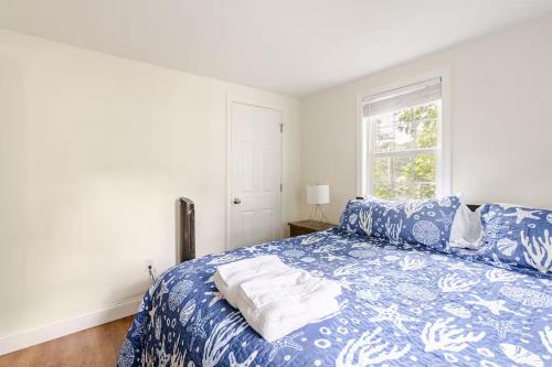 a bedroom with a blue and white bed with a window at Dennis Beach House - Walk to Beach - Pet Friendly in Dennis