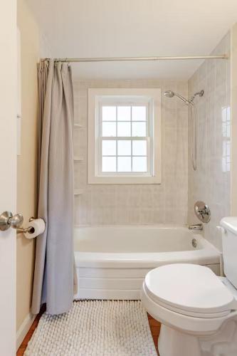 a bathroom with a tub and a toilet and a window at Dennis Beach House - Walk to Beach - Pet Friendly in Dennis